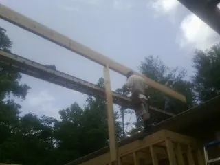 Carpenter setting a ridge beam over a new addition frame — Ice Dam Removal by Roofing Brothers in Harris
