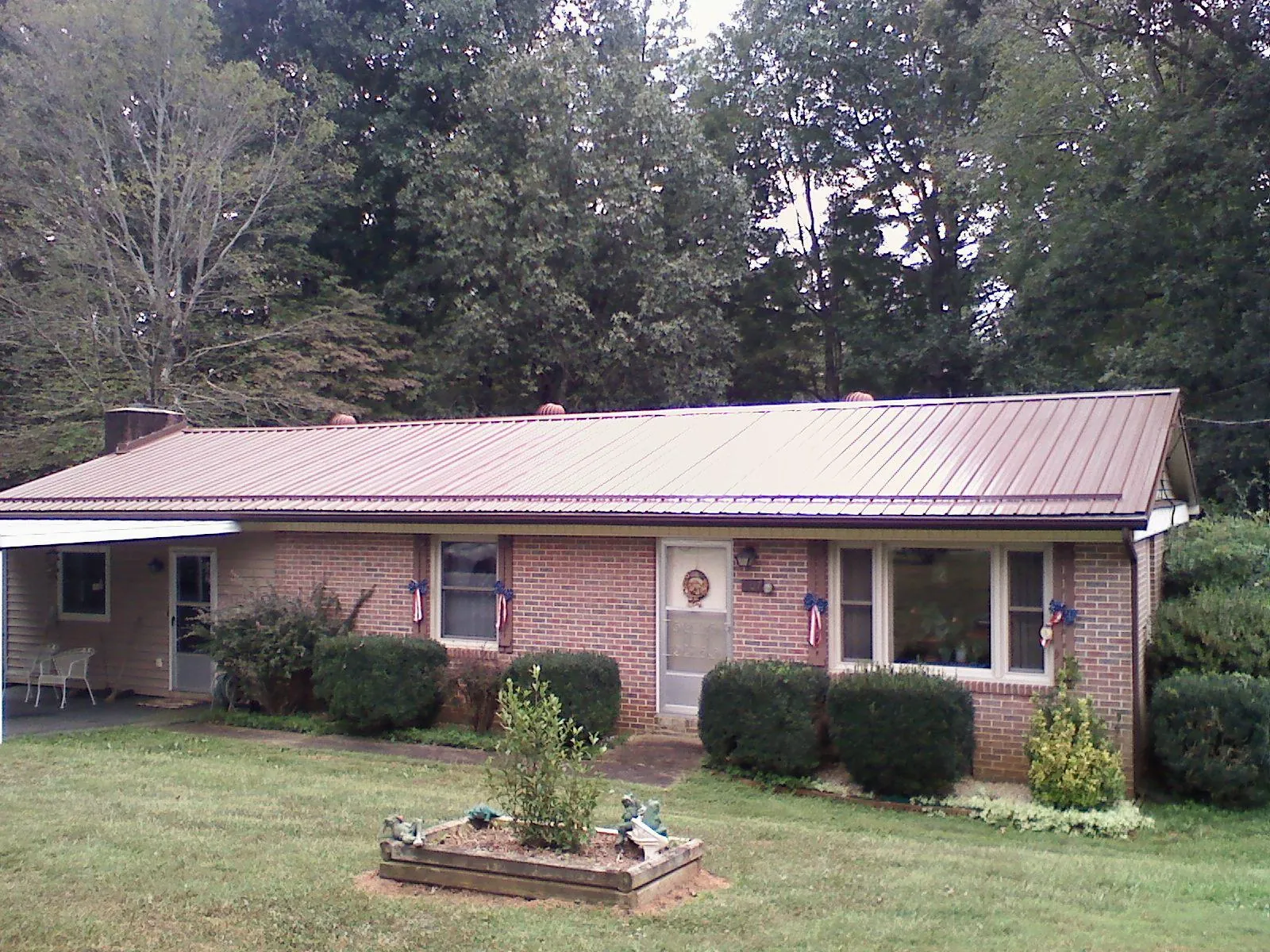 Bronze metal roof on a brick ranch home with a carport in Harris