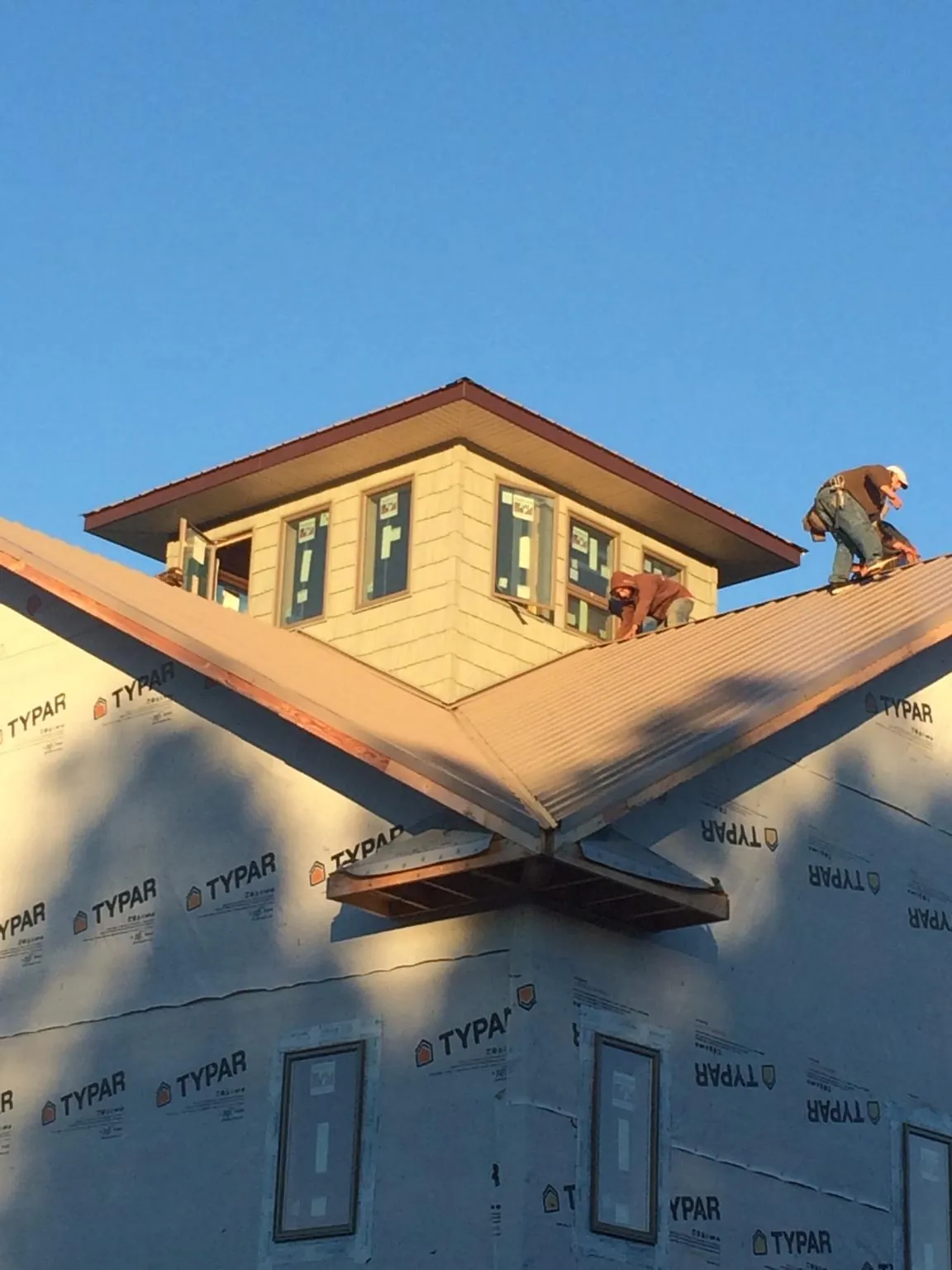 Roofers working around a rooftop cupola on a new metal roof at sunset — Roof Waterproofing in Harris by Roofing Brothers